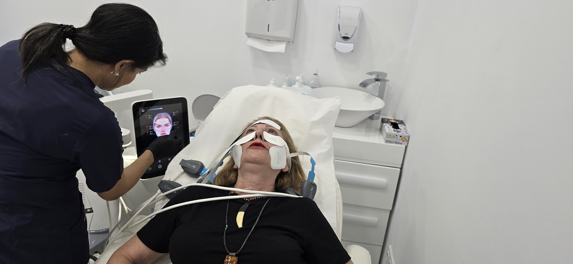 EMFACE Tratamiento para la flacidez facial Se trabaja en los pómulos, en la frente y en la papada Este tratamiento es una combinación de radiofrecuencia sincronizada y tecnología HIFES™ para combatir la flacidez facial y el descolgamiento muscular del rostro. EMFACE es un innovador tratamiento diseñado para abordar la flacidez facial y el descolgamiento muscular del rostro. Es único en su clase por ser el primer procedimiento que combina radiofrecuencia sincronizada (RF) y tecnología HIFES™, sin necesidad de agujas. Esta doble acción permite trabajar de manera simultánea tanto en la piel como en los músculos faciales, ofreciendo una solución efectiva y cómoda para rejuvenecer el rostro desde sus cimientos. El funcionamiento de EMFACE se centra en la mejora de la calidad muscular. A través de contracciones selectivas de los músculos y el aumento de la densidad y calidad de la estructura muscular, este tratamiento restaura el soporte natural de los tejidos faciales. Como resultado, el rostro recupera firmeza y elevación, devolviendo una apariencia rejuvenecida y redefinida, al tiempo que mejora la estructura subyacente de manera segura y no invasiva.